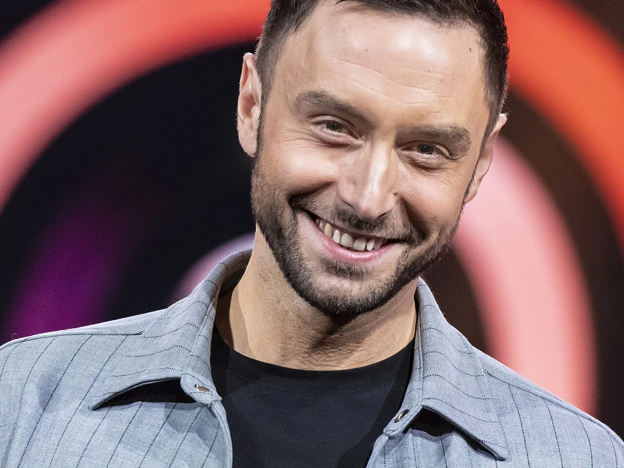 Måns Zelmerlöw ler på scenen under Melodifestivalen 2025 i Malmö